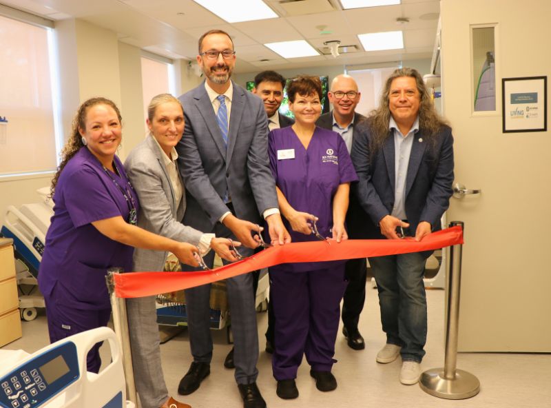 people standing behind a ribbon with scissors