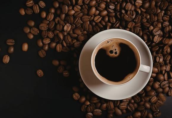 cup of coffee surrounded by coffee beans
