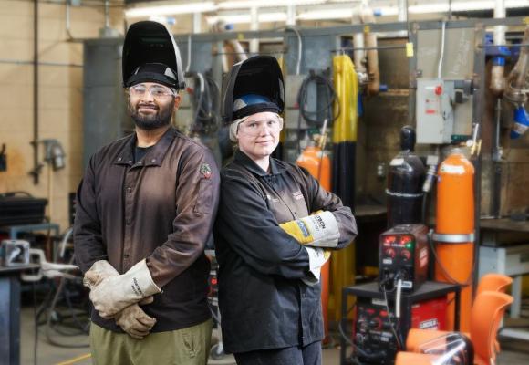 Two skilled trades students standing back to back