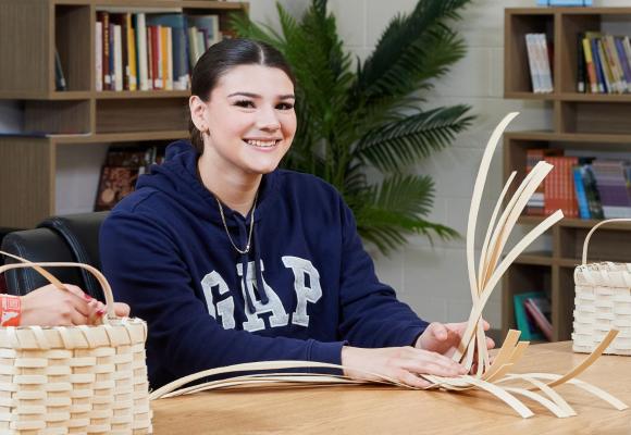 student smiling while making basket