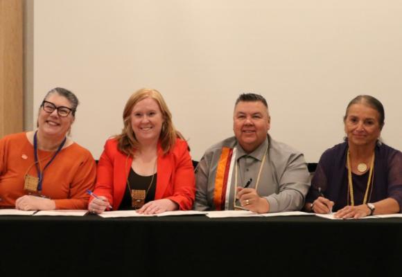 four people signing agreement on table