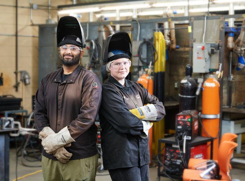 Two skilled trades students standing back to back