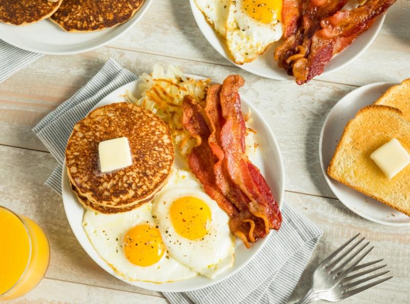 plate of fried eggs, bacon, and pancakes